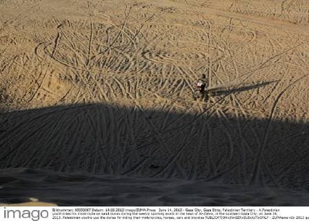 June 14, 2013 - Gaza City, Gaza Strip, Palestinian Territory - A Palestinian youth rides his motorcycle on sand dunes during the weekly sporting event in the town of Al-Zahra, in the southern Gaza City, on June 14, 2013. Palestinian youths use the dunes for riding their motorcycles, horses, cars and bicycles  - ZUMAews