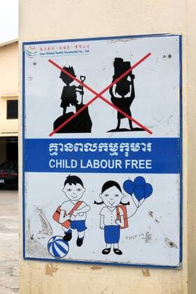 Schild gegen Kinderarbeit am Tor einer Textilfabrik im Industrieviertel Pochentong in Phnom Penh, Kambodscha