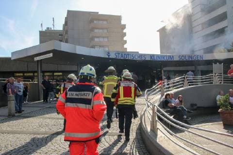 Rescue workers rush to the main entrance of the Municipal Hospital Solingen in the background simulated smoke rises from one of the patient rooms In a large-scale exercise in the Solingen Hospital tested a total of 450 participants an emergency scenario with fire and the rescue of patients in the first floor of the house G of the hospital Solingen broke fire sim Copyright: xdnet_kwkx