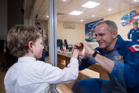 News Themen der Woche KW48 News Bilder des Tages Expedition 58 Flight Engineer David Saint-Jacques of the Canadian Space Agency (CSA), right, who is in quarantine, makes a heart with his hands for his son, at the conclusion of a press conference, on December 2, 2018, at the Cosmonaut Hotel in Baikonur, Kazakhstan. Launch of the Soyuz rocket is scheduled for December 3 and will carry Saint-Jacques, Soyuz Commander Oleg Kononenko of Roscosmos, and Flight Engineer Anne McClain of NASA into orbit to begin their six and a half month mission on the International Space Station. NASA WAX2018120212 AUBREYxGEMIGNANI