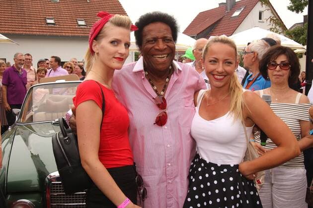 traditional festival Golden Oldies in Wettenberg near Giessen, Hesse, Germany singer Roberto Blanco in a good mood with two young ladies in arms in front of a Mercedes Oldtimer
