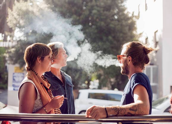 Friends smoking while standing outdoors on sunny day model released Symbolfoto AJOF00383