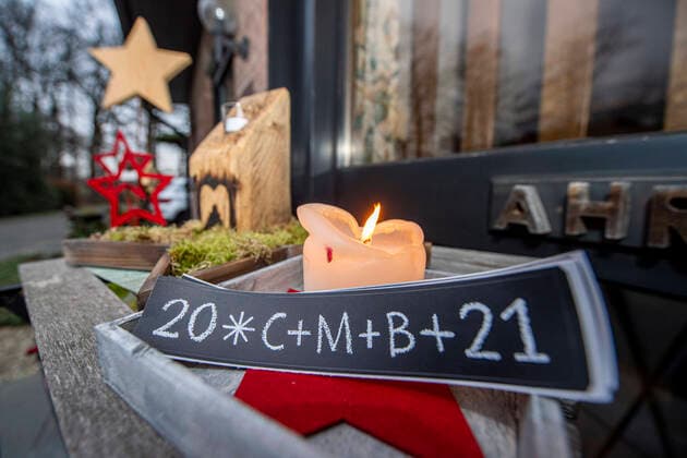 Carol singing in the Corona season Stickers with the blessing of the carol singers lie on a table in front of a door, a candle burns in front of it The motto of this years carol singing campaign is Our star shines brighter Copyright: xInderlied Kirchner-Mediax
