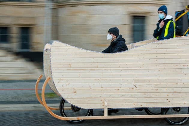 GERMANY, LOWER SAXONY, HANOVER, 22 01 2021 Sledge demonstration by Fridays for Future Hanover Hanover city centre A dummy sledge made of wood and mounted on a tricycle rides in front of the New Town Hall Under the motto Do you still know why? Fridays for Future demonstrates with sledges in the city centr