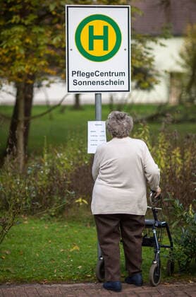 Dummy bus stop for dementia patients A senior citizen looks at the timetable on a bus stop sign in the garden of the Sonnenschein care center in Gerstungen Thuringia on 29 10 2014 The dummy helps to protect dementia residents from wandering Gerstungen Thuringia GERMANY