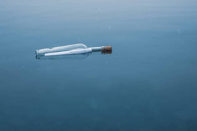 Bottle with message in bottle in winter at lake, snowy message in bottle