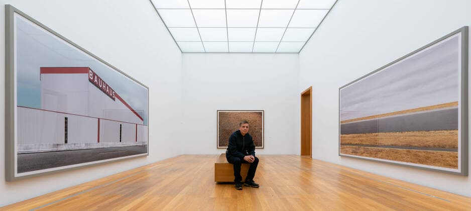 Photographer Andreas Gursky sits in front of his works l r Bauhaus 2020 , Untitled III 1996 and Rhine III 2018 at the Museum der bildenden Künste MdbK in Leipzig The MdbK presents Andreas Gursky from 25 03 22 08 2021 the first insti