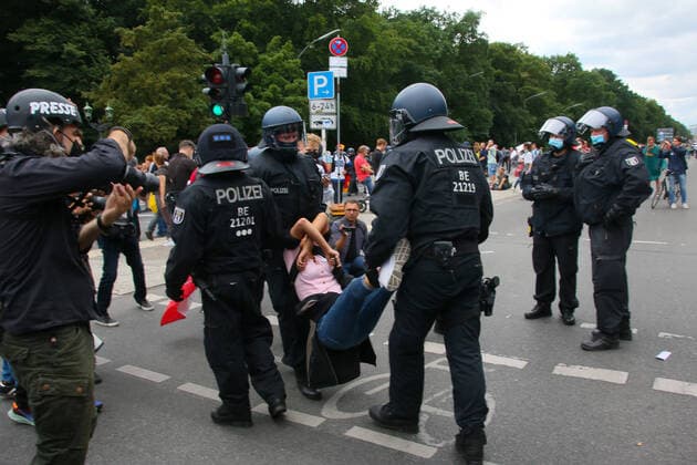 after the third request of the police a young woman is carried away by the police forbidden lateral thinkers demo on the street of the 17 june at the sigessäule