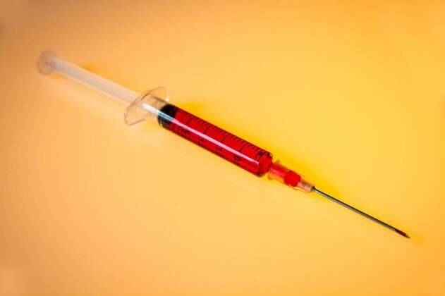 Syringe with blood on orange background, 13.10.2020, Copyright: xdaboostx Panthermedia26661598