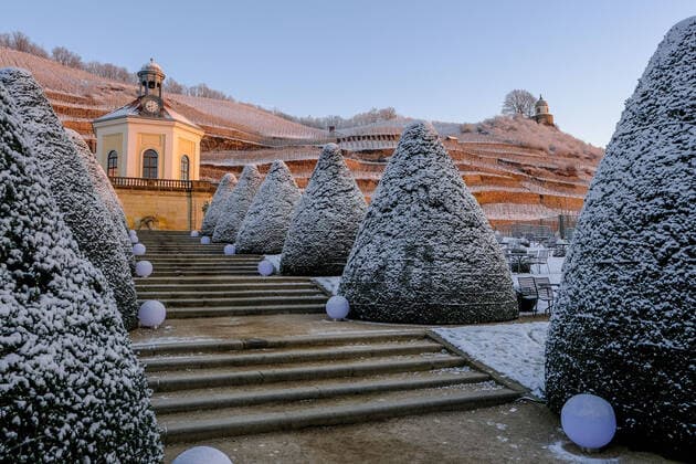 The morning sun illuminates the slightly snowy vineyards of Wackerbarth Castle with the Belvedere and the Jacobstein in Radebeul Saxony on 26 12 2021.