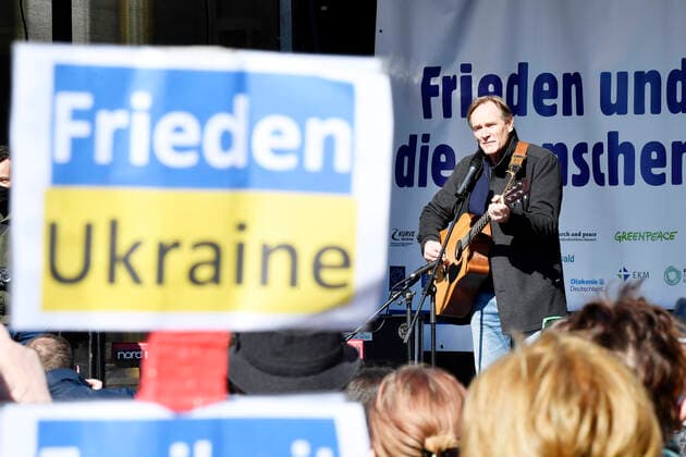 Demonstration Peace and solidarity for the people in Ukraine in Leipzig 13 03 2022 Leipzigs mayor Burkhard Jung at the demonstration against the war in Ukraine in Leipzig 13 03 2022 with a guitar in front of a sign Peace and solidarity for the people in Ukraine Stop the war In the foreground in sign with the i