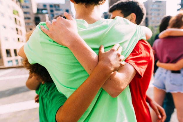 IMAGO Creative: Welttag für psychische Gesundheit am 10. Oktober Multiracial friends hugging each other standing on footpath model released, Symbolfoto, MEUF06150