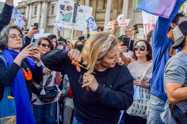 September 24, 2022, London, United Kingdom: A protester cuts off a lock of her hair during the demonstration. Thousands of Iranians and other protesters gathered in Trafalgar Square in response to the death of Mahsa Amini, who died in police custody in Iran after being detained for allegedly not wearing a head scarf (hijab) properly in public. London United Kingdom - ZUMAs197 20220924_zaa_s197_220 Copyright: xVukxValcicx