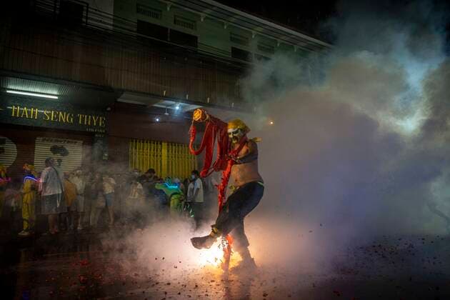 October 3, 2022, Bangkok, Bangkok, Thailand: Festival goers look on as a man wearing traditional face paint dances while fireworks wrapped around his body explode. The annual vegetarian festival, celebrated throughout parts of Thailand that have historical ethnic Chinese influence, has been observed in Thailand since the 19th century draws from Taoist and Confucian beliefs and traditions. Bangkok Thailand - ZUMAt128 20221003_zap_t128_002 Copyright: xAdryelxTalamantesx