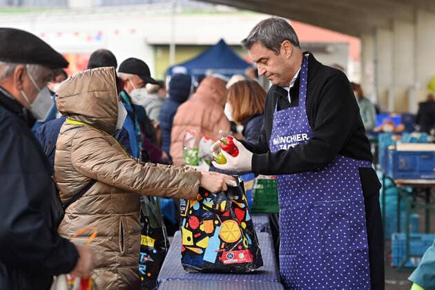 Markus SOEDER Prime Minister of Bavaria and CSU Chairman visits the Muenchner Tafel on 16 11 2022 Markus SOEDER Prime Minister of Bavaria and CSU Chairman with apron at the distribution of food,vegetables Needy people wait in front of the Muenchner Tafel in front of the wholesale market Munich for the food distribution queue people queue