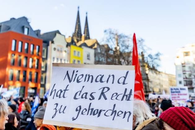 Sign Nobody has the right to obey Action Weekend öStop the Killing for Ceasefire and Negotiations ˜ by Deutsche Friedensgesellschaft Vereinigte KriegsdienstgegnerInnen at the Alter Markt in Cologne 25 02 2023 Cologne Altstadt NRW Germany