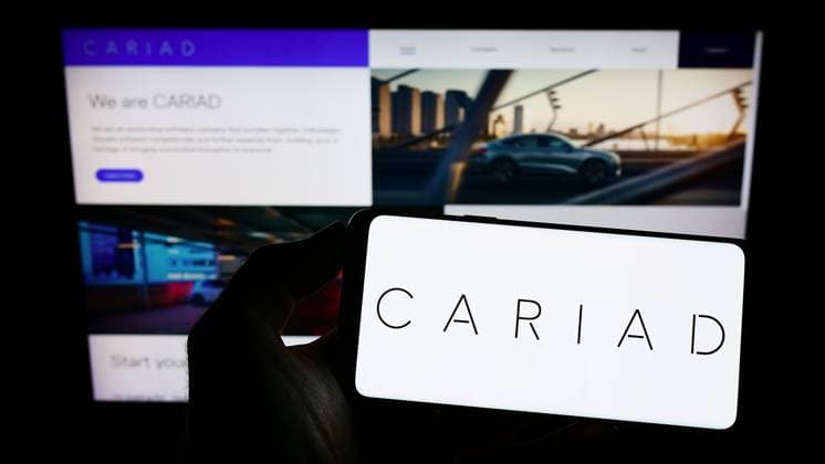Person holding cellphone with logo of German automotive software company Cariad SE on screen. Stuttgart, Germany - 10-15-2022: Person holding cellphone with logo of German automotive software company Cariad SE on screen in front of business webpage. Focus on phone display. Copyright: xZoonar.com TimonxSchneiderx 19287755