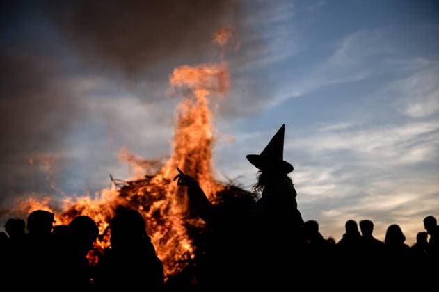 30 04 2023 Weimarer Land Bergern A girl dressed as a witch with a witchs hat stands out as a silhouette in front of a traditional fire for Walpurgis Night