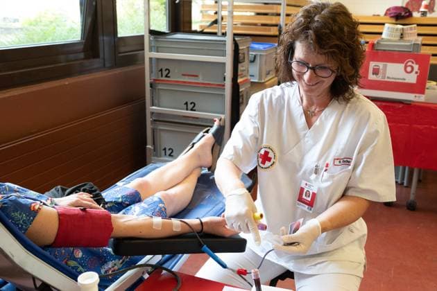 An employee of the DRK blood donation service puts the cannula on the arm of the donor, theme photos BLUTSPENDE on the occasion of the blood donation campaign of the German Red Cross with the action missingtype for the World Blood Donor Day on June 14, 2023, photo session on 05 06 2023 in the school center Pesch in Cologne,