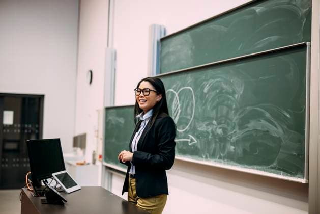 Smiling businesswoman standing in front of greenboard at auditorium model released, Symbolfoto property released, JOSEF21463