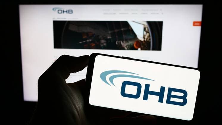 Person holding cellphone with logo of German aerospace company OHB SE on screen. Stuttgart, Germany - 09-10-2023: Person holding cellphone with logo of German aerospace company OHB SE on screen in front of business webpage. Focus on phone display. Copyright: xZoonar.com TimonxSchneiderx 21082507