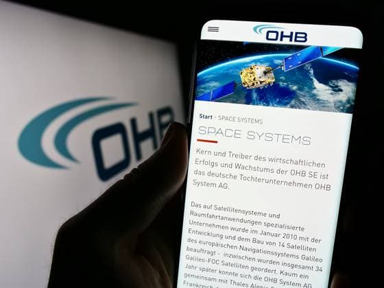 Person holding cellphone with webpage of German aerospace company OHB SE on screen. Stuttgart, Germany - 09-10-2023: Person holding cellphone with webpage of German aerospace company OHB SE on screen in front of business logo. Focus on center of phone display. Copyright: xZoonar.com TimonxSchneiderx 21082529
