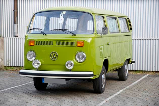 Oldtimer VW Bulli T2 a Very Maintained Grasshopper gruener VW Bulli T2 is at a marked Car park before a white Corrugated iron wall Food