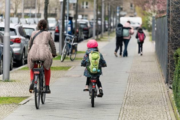 2024 03 21,Berlin,a woman and child are each riding a bicycle on the sidewalk