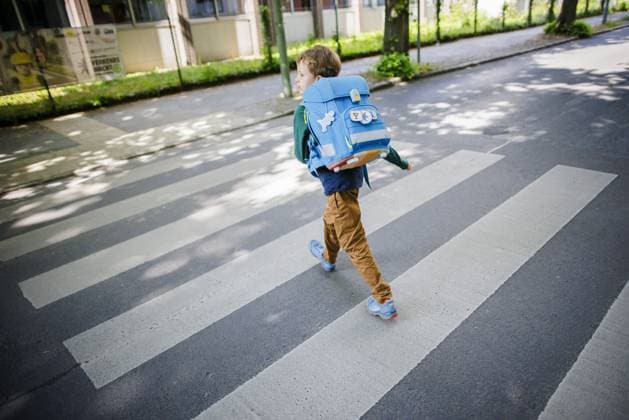 Symbolic photo of a schoolchild in traffic A six-year-old boy walks with his satchel on his back across a pedestrian crosswalk in front of an elementary school Berlin, 08 05 2024 Berlin Germany Copyright: xThomasxTrutschelxphotothek.dex
