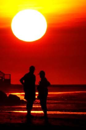 May 23, 2024, Isle Of Palms, Sc, United States: A couple silhouetted by the sunrise, watch as the fireball of a sun, rises over the Atlantic Ocean horizon, May 23, 2024 in Isle of Palms, South Carolina. Isle Of Palms United States - ZUMAe02_ 20240523_zaf_e02_009 Copyright: xRichardxEllisx