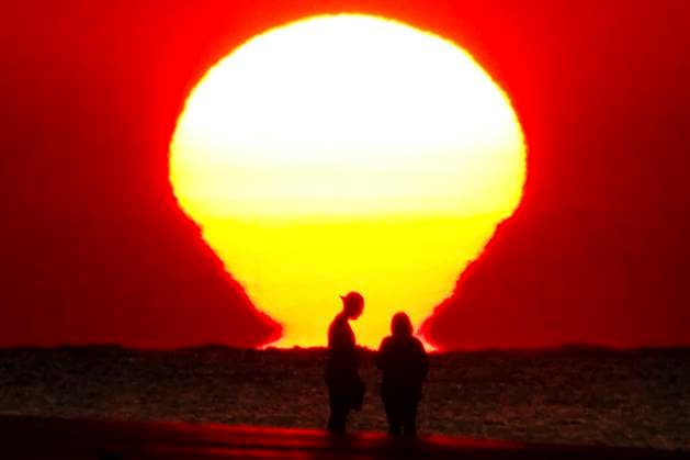 May 29, 2024, Isle Of Palms, Sc, United States: The sun rises over the Atlantic Ocean reflected on the water silhouetting a couple on the beach as a heat wave sweeps across the region bringing temperatures into the 90Ã¢â‚¬â ¢s, May 29, 2024 in Isle of Palms, South Carolina. Isle Of Palms United States - ZUMAe02_ 20240529_zaf_e02_008 Copyright: xRichardxEllisx