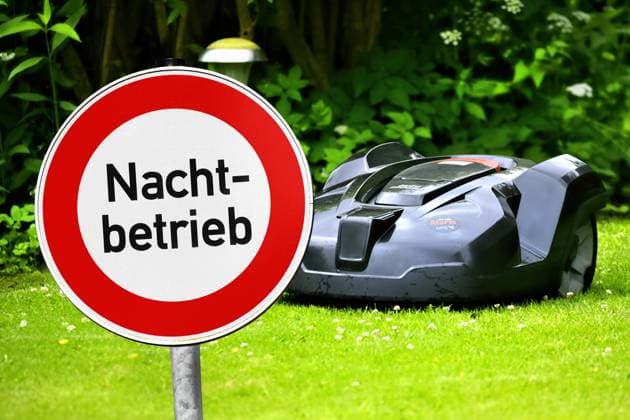 PHOTOMONTAGE, robot mower on a lawn and prohibition sign with the inscription night operation ** NUR FUER REDAKTIONELLE ZWECKE ** EDITORIAL USE ONLY **