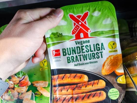 Bavaria, Germany - July 10, 2024: Customer holding a pack of vegan Bundesliga bratwurst from the Rügenwalder Mühle brand. Meat substitute