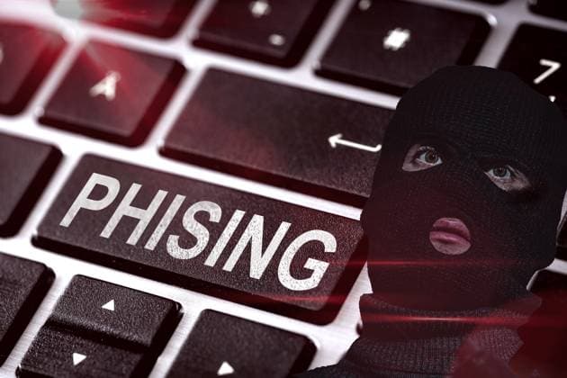 Bavaria, Germany - August 18, 2024: Keyboard of a computer, or laptop, next to a masked person with a black robber mask. Concept phishing online on the internet - fake websites, emails or fake short messages via WhatsApp. PHOTOMONTAGE