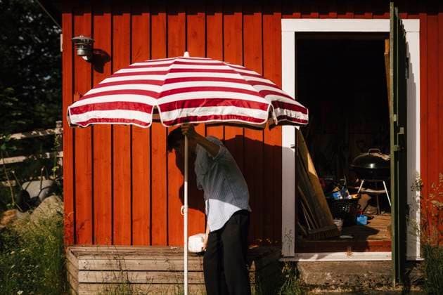 Man unfolding parasol in front of shed , model released , property released Copyright: xJohnerxImagesx , johner2508594.jpg 