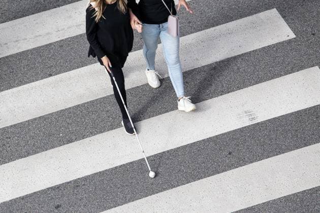 Szene einer blinden Frau, die auf einem Zebrastreifen geht und von einer anderen Person mit ihrem weißen Stock unterstützt wird. Hilfe in den frühen Stadien der Erblindung Scene of a Blind woman walking on zebra crossing helped by another person using her white cane. Help in the early stages of blindness Copyright: imageBROKER AndresxVictorero ibxiqx09628576.jpg