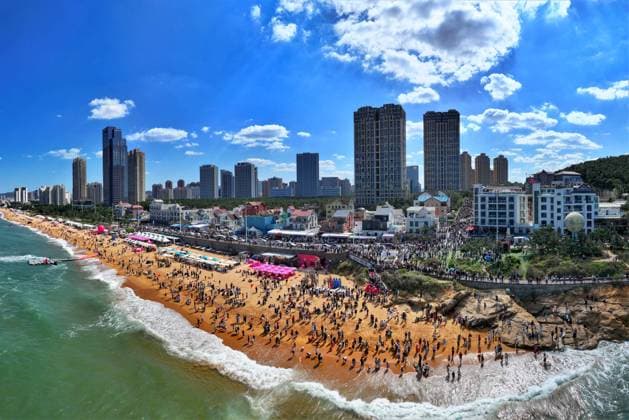 (241003) -- BEIJING, Oct. 3, 2024 -- An aerial drone photo shows people enjoying themselves at a beach in Weihai, east China s Shandong Province, Oct. 2, 2024. (Photo by Xinhua) Xinhua Headlines: Chinese revel in culture, tourism feast during week-long National Day holiday ZhuxChunxiao