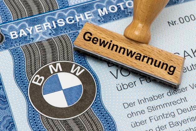 Profit warning for BMW A wooden stamp is labeled with the words profit warning, above a BMW share with company logo Symbolic image