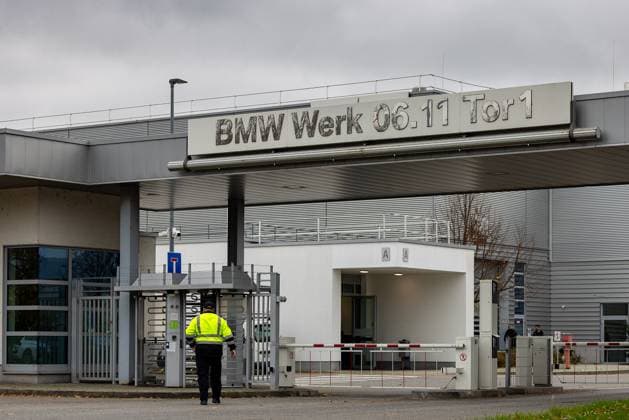 Automotive industry Entrance gate 1 of the BMW plant in Regensburg An employee in a yellow high-visibility vest enters the plant premises through a turnstile The modern building shows the company sign BMW Plant 06 11 Gate 1 on a gray background Regensburg Burgweinting Harting Bavaria Germany 20241030-286A3343-M4000