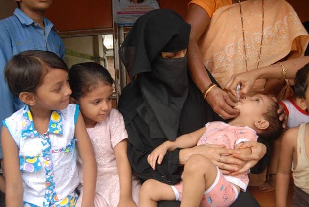 A Muslim woman holds her child in her hands to administer Polio vaccination during Pulse Polio drive in Bombay now Mumbai, Maharashtra, India Copyright: xAkellaxSrinivas DinodiaxPhotox