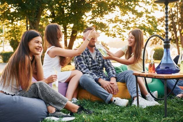 Drinking game. Group of young people have a party in the park at summer daytime., model released, , 51356710.jpg, group, people, hookah, smoking, culture, party, drink, cocktails, sitting, relaxing, resting, alcohol, beverage, armchair, bags, fun, together, outdoors, outside, summer, park, green, grass, caucasian, white, european, ethnicity, casual, clothes, wear, joy, cheerful, wellness, wellbeing, nice, positive, emotions, friends, weekend, leisure, free, time, sunlight, sunshine, beautiful, conversation, talking, communicating, socializing, young RECORD DATE NOT STATED