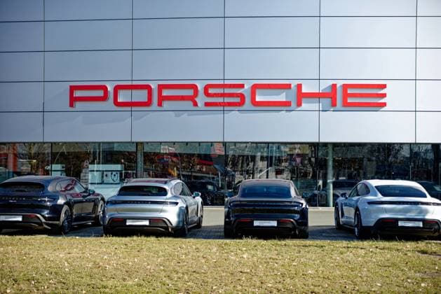 Logo the Car brand Porsche to the Facade of Porsche Center in Nuremberg with before that parked Vehicles 1104401528