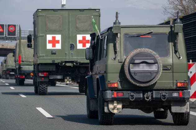 A9, Germany - 23 March 2025: Military vehicles with camouflage livery and Lithuanian license plates (unrecognizable) are driving on the A9. In the convoy is a medical vehicle with two red crosses and a green flag.