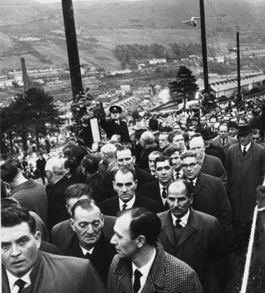 Aberfan - The nation mourns. Today the nation mour Aberfan - The nation mourns. Today the nation mourned the lost generation of Aberfan, and in the cemetery on the mountain above the village 80 little coffins were being lowered into two mass graves this afternoon. South Wales has seen many painful sights since men first started to wrest coal from its valleys, but never one like this. As the coffins were placed in position at the graveside on a clear, cold day one policewoman was so overcome that she had to be led away. As well as 80 children - all victims of last Fridays disaster - an adult, a mother, was also buried today. Pic shows Mourners make their way to the cemetery for the burial service at Aberfan today. Retrocon British Views.  Copyright: xNotxKnownx