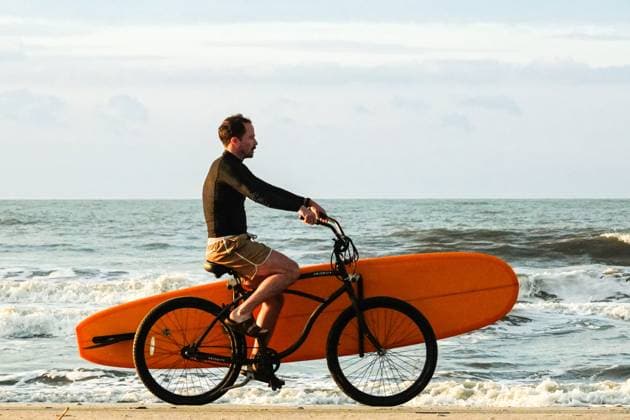 May 14, 2025, Isle Of Palms, Sc, United States: A surfer rides his beach cruiser carrying a surfboard to the swells along Front beach, May 14, 2025 in Isle of Palms, South Carolina. Isle Of Palms United States - ZUMAe02_ 20250514_zaf_e02_003 Copyright: xRichardxEllisx