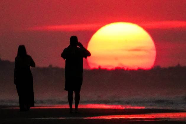 May 20, 2025, Isle Of Palms, Sc, United States: A couple, silhouetted by the sunrise takes a photo as the sun climbs over the horizon at Front Beach, May 20, 2025 in Isle of Palms, South Carolina. Isle Of Palms United States - ZUMAe02_ 20250520_zaf_e02_005 Copyright: xRichardxEllisx