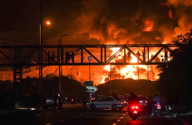 Bilder des Jahres 2025, News 06 Juni News Themen der Woche KW24 ?Iranians looking as a plume of heavy smoke and fire rise from an oil refinery in Tehran, after it was hit in an overnight Israeli strike, on Sunday on June 15, 2025.  IRN2025061504 AhmadxHatefi