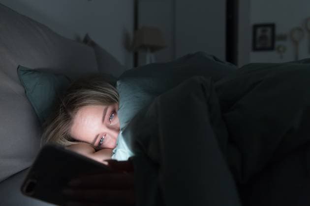 schläfrige, müde Frau, die unter der Decke im Bett liegt und spätabends ihr Smartphone benutzt, kann nicht schlafen. Portrait of young sleepy tired woman lying in bed under the blanket using smartphone at late night, can not sleep. Insomnia, nomophobia, sleep disorder concept. Dependency on a cell phone (License=RF) ,model released, Symbolfoto Copyright: xZoonar.com DmitriixMarchenkox 23711594 ,model released, Symbolfoto ,property released