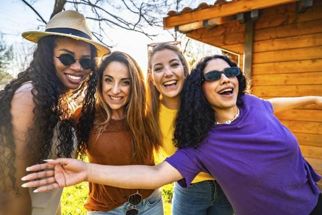 Vier multiethnische Freundinnen genießen einen sonnigen Tag in einem Garten, lächeln und umarmen sich Four multi ethnic female friends are enjoying a sunny day in a garden, smiling and embracing each other Copyright: imageBROKER UnaixHuizi ibxuhu14215399.jpg ,model released, Symbolfoto ,property released