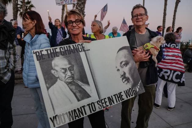 July 17, 2025, Santa Barbara, Ca, USA: A Protesting woman holds a sign that says, â€oeBe the Change You want to see in the worldâ€� with photos of Gandhi and Martin Luther King Jr. on the poster. Next to her a man holds a little dog. They joined over a thousand people gathered for the Good Trouble protest at Stearns Wharf and State St., stretching out along Cabrillo Blvd. in Santa Barbara California on July 17, 2025, calling for ICE out of Santa Barbara, impeachment of President Trump, and other issues. Santa Barbara USA - ZUMAk144 20250717_znp_k144_021 Copyright: xAmyxKatzx